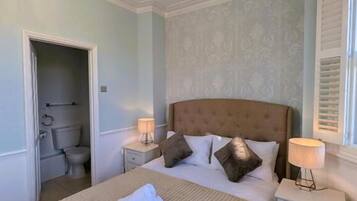 A neatly made bed with a brown headboard, two bedside tables with lamps, and a chandelier.