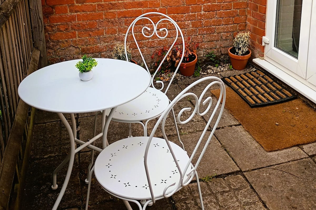 A brick wall, a white door, and a small patio with a table and chairs.