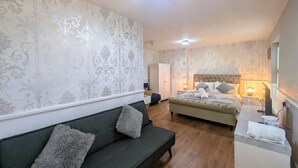 Un dormitorio con cama, sofá, mesita de noche y velador.
