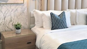 Une chambre à coucher avec un grand lit, une table de chevet, un tableau accroché au mur et un luminaire suspendu au plafond.