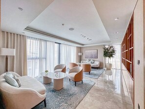 A modern hotel room with a large window, a sofa, a coffee table, and a dining area. - FIRST CLASS | 1BR | Near Dubai Mall & Burj Khalifa (Downtown)