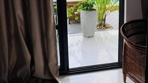 Une pièce dotée d’une grande porte-fenêtre coulissante donnant sur un balcon avec une piscine et des plantes en pot.