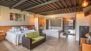 Ein modernes Hotelzimmer mit einem großen Bett, einer Couch, einer Badewanne und einem Essbereich.