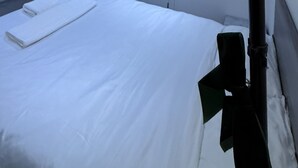 Ein Hotelzimmer mit Bett, Nachttisch, Lampe, einer Tür und einer Wand-Klimaanlage.