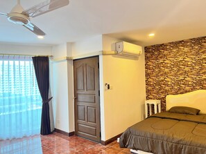 Ein Schlafzimmer mit Bett, Deckenventilator, Steinwand und Klimaanlage.
