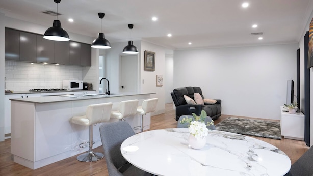 A modern kitchen with white cabinetry, a central island with bar stools, and pendant lighting.
