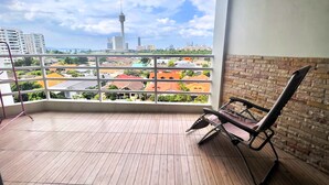 Un balcon offrant une vue sur le paysage urbain, avec notamment une tour et divers bâtiments.