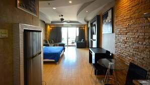 Une chambre d’hôtel moderne équipée d’un lit, d’un bureau, d’une chaise, d’un réfrigérateur et d’un mur en briques.