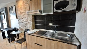 Une cuisine moderne dotée d’un évier en acier inoxydable, de meubles en bois, d’un pare-feu noir et d’un mur en briques.
