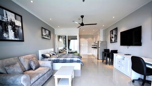 Ein modernes Schlafzimmer mit Bett, Sofa, Schreibtisch und Fernseher.