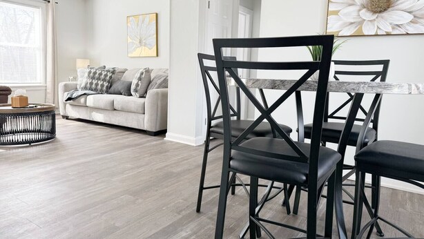 A modern living room with a grey sofa, a round coffee table, and a dining area with black chairs and a marble table. - Riverside A2 - QUEEN 2BD/1BA Apt near River (Evansville)