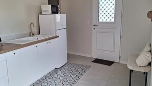 Une cuisine moderne avec des meubles blancs, un plafond en bois, un four à micro-ondes et un réfrigérateur.
