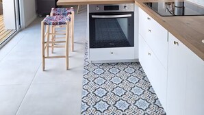 Une cuisine moderne avec un plan de travail en bois, un four encastré et un sol à motifs.