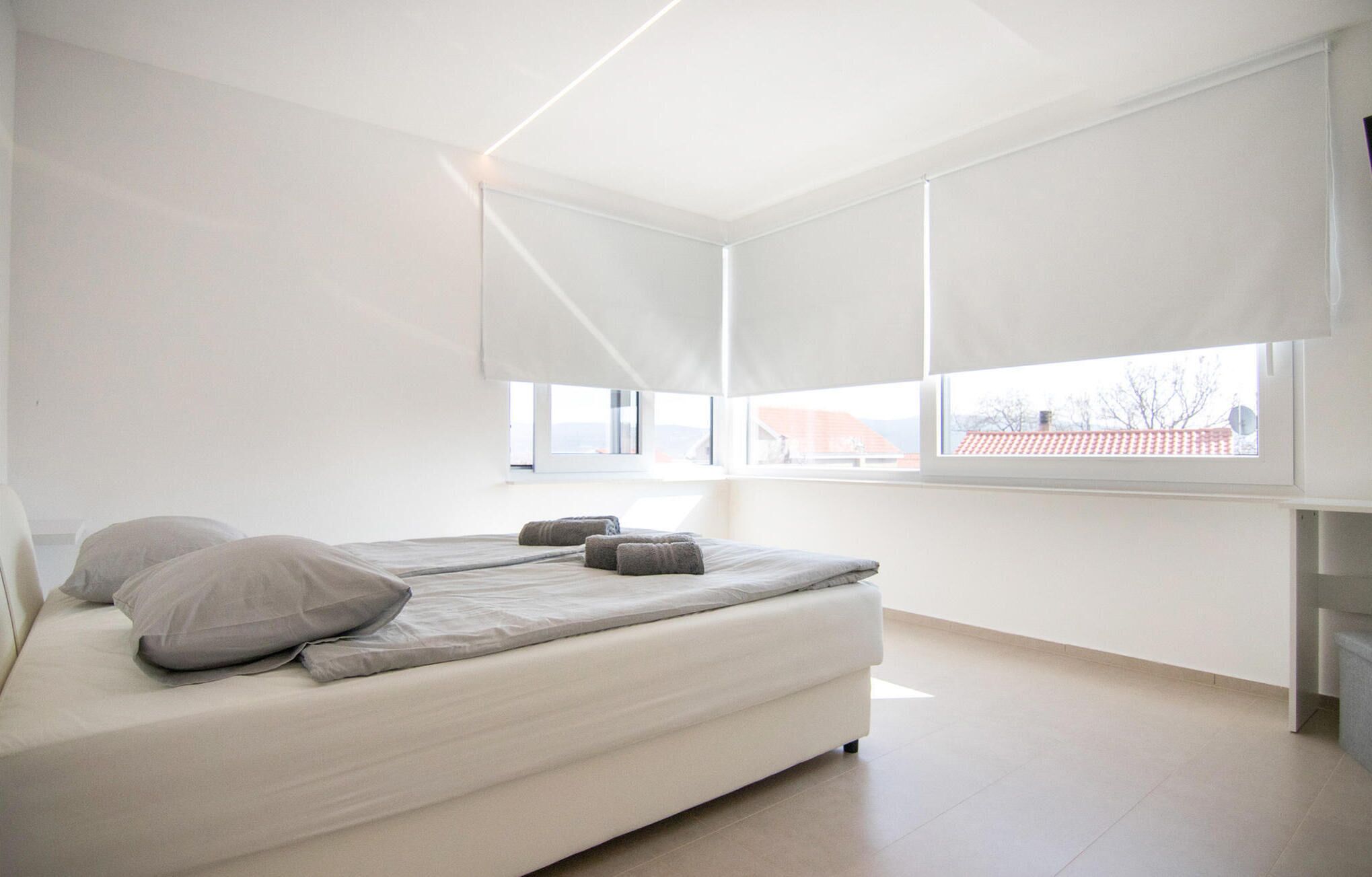 Un dormitorio con cama, almohadas, una ventana y vistas al exterior.