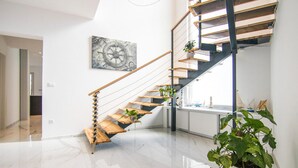 A modern interior with a wooden staircase, a large window, and a potted plant. - Beautiful home in Krk with sauna (Krk)