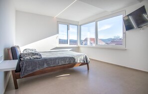 Une chambre à coucher avec un lit, un bureau et un téléviseur fixé au mur.
