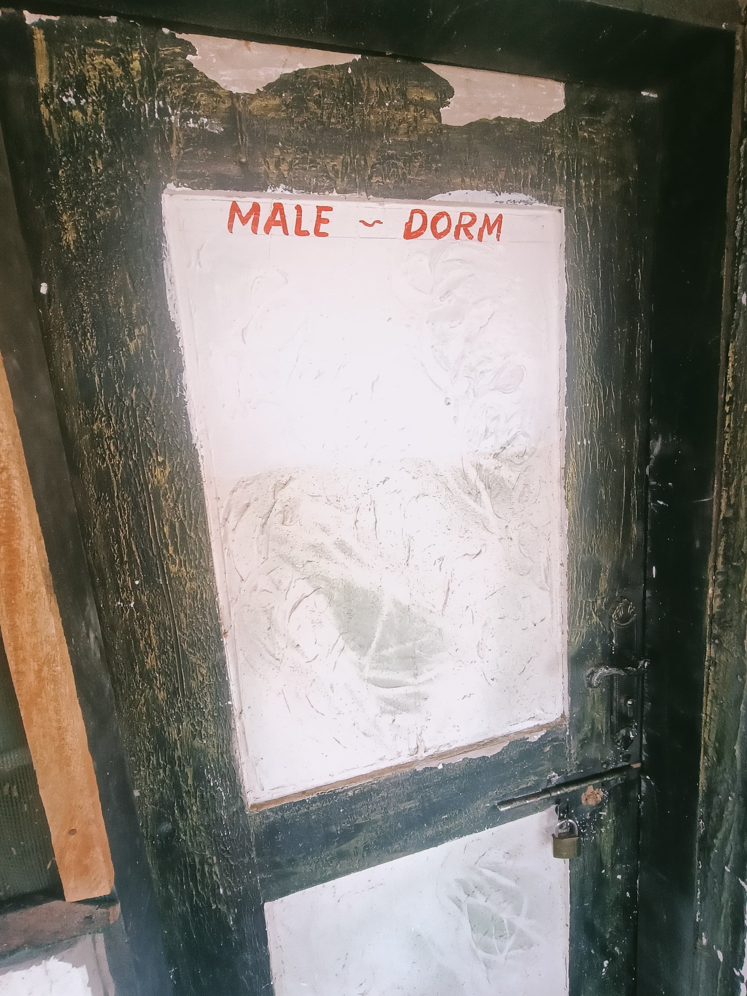 A door with a white sign that reads "MALE ~ DORM".