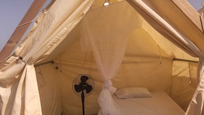 A tent with a bed, a fan, and a bottle. - Babalao Beach Resort  Backpackers & Tent (Malindi)