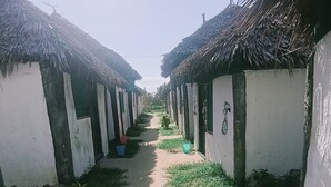 A narrow pathway flanked by thatched-roof huts with white walls and green doors. - Babalao Beach Resort  Backpackers & Tent (Malindi)