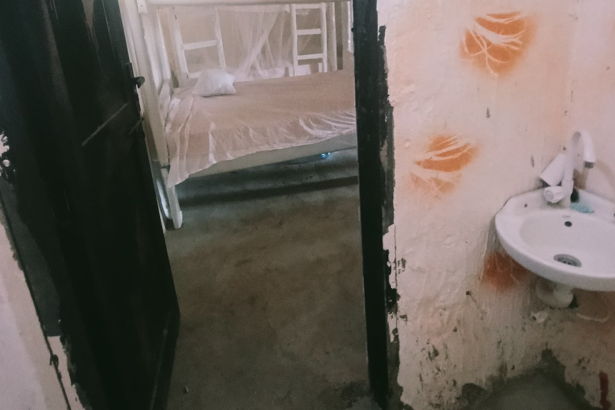 Una habitación con un lavabo blanco, una puerta negra y un techo en construcción.