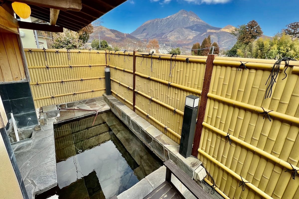 A traditional Japanese onsen with a bamboo fence and stone basin.