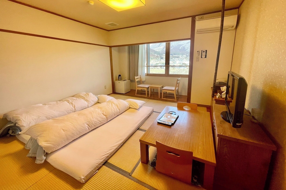 A hotel room with a bed, a desk, a chair, and a TV.