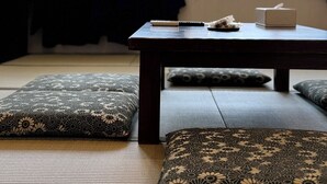 Une pièce avec des tatamis, une table sur laquelle se trouve une boîte de mouchoirs, et une vue sur les montagnes par de grandes fenêtres.