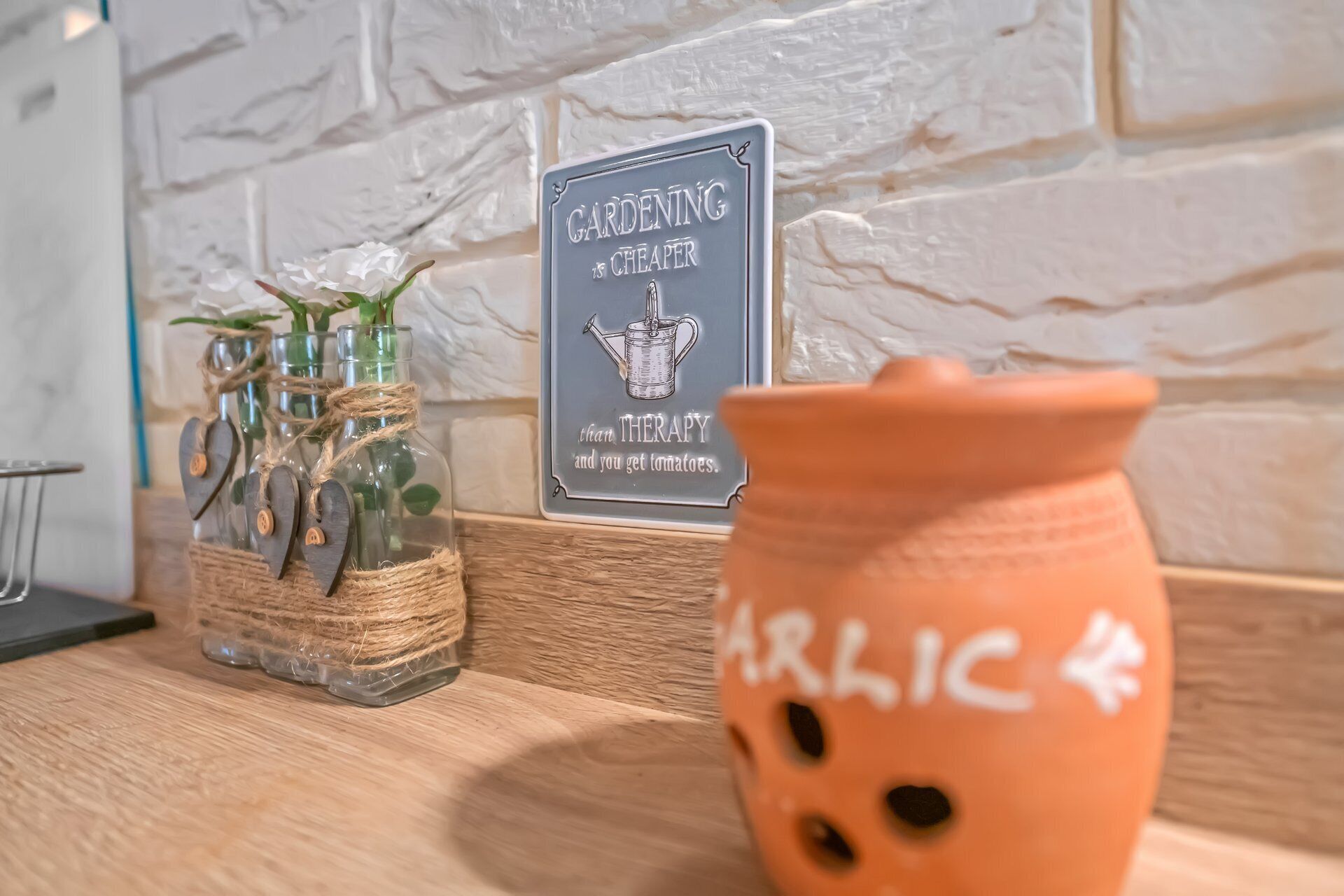 Une cuisine rustique, avec une pancarte sur laquelle on peut lire : « Le JARDINAGE coûte moins cher que la THÉRAPIE, et en plus, vous avez des tomates. »