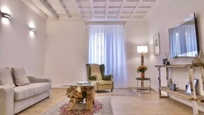 Una sala de estar con un sofá, una mesa de centro, una silla, un televisor y una lámpara.