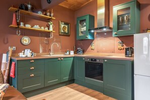 A kitchen with green cabinets, a stainless steel sink, and a built-in oven.