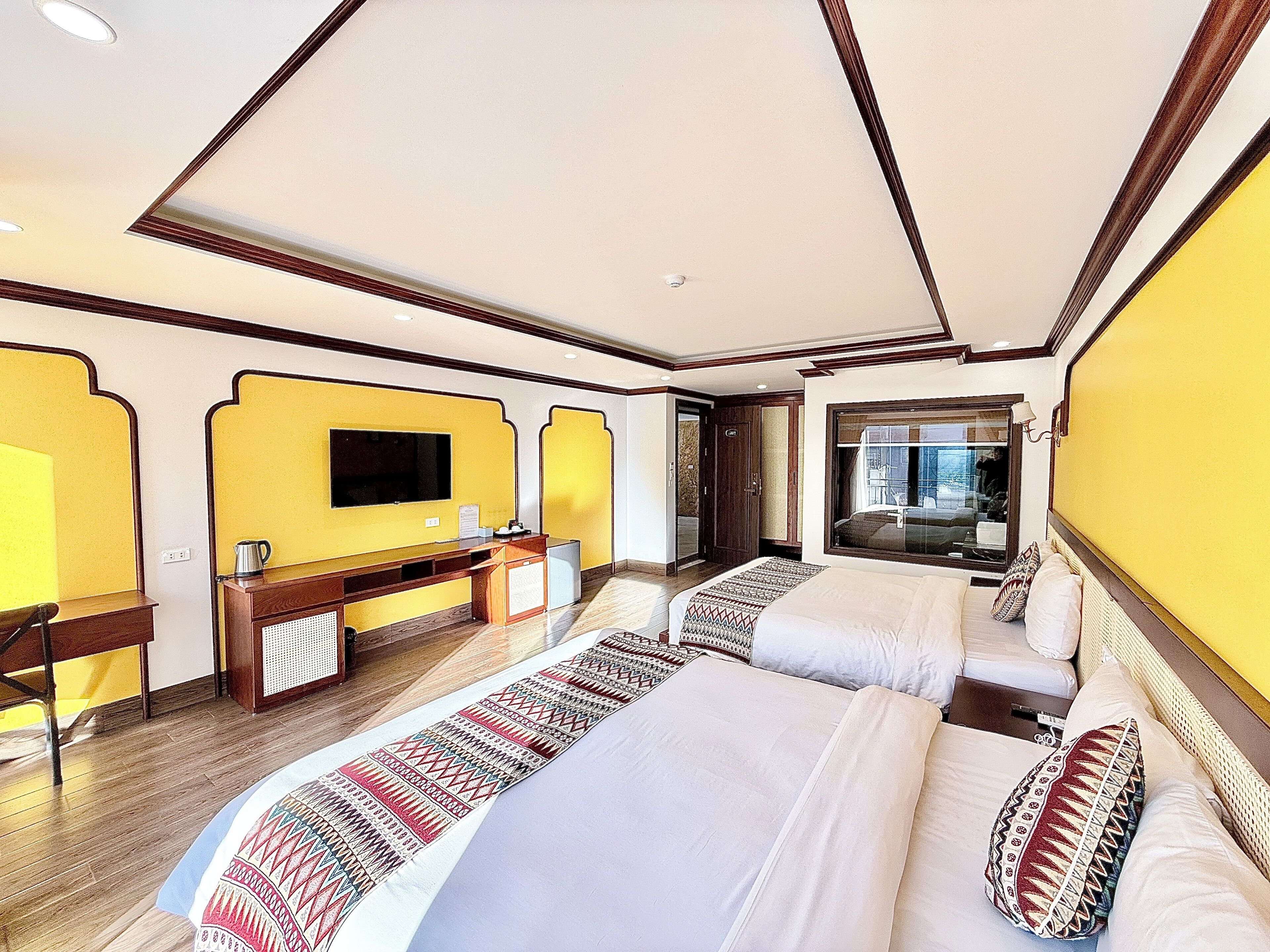 Une chambre d’hôtel avec deux lits, une télévision, un bureau avec un ordinateur et une fenêtre donnant sur un beau paysage.