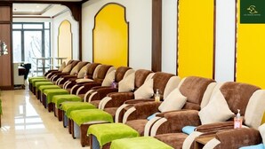 A row of massage chairs with green footrests, a reception desk, and a yellow accent wall. - Le Chapa Hotel & Spa (Sa Pa)
