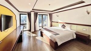 A modern hotel room with a large bed, a flat-screen TV, and a balcony with curtains. - Le Chapa Hotel & Spa (Sa Pa)