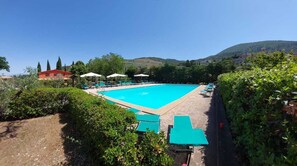 Una piscina al aire libre de temporada, sombrillas