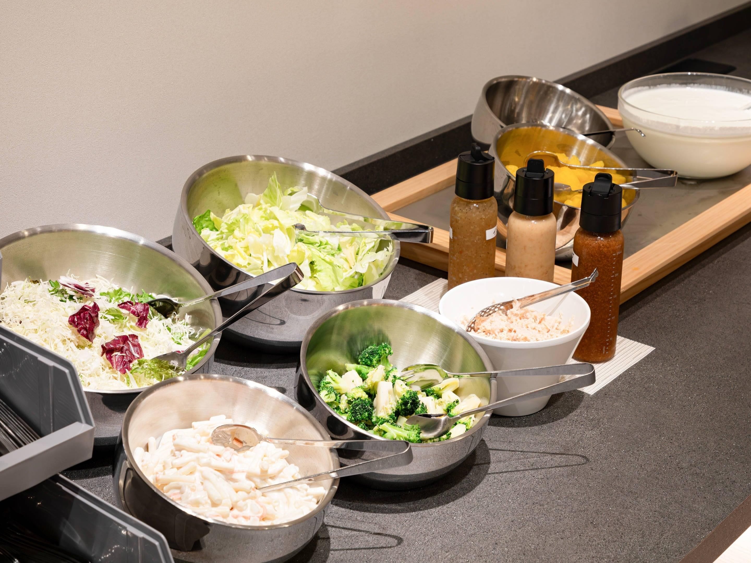 Une table de buffet proposant divers plats, notamment des pâtes, des légumes et des sauces.