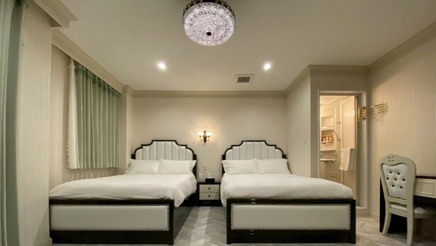 Une chambre d’hôtel avec deux lits, un lustre, un bureau et une chaise.