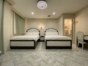 A hotel room with two beds, a chandelier, a desk, and a chair.