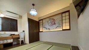 Une pièce avec des tatamis, une armoire en bois, un bureau avec une chaise, un climatiseur fixé au mur et un tableau décoratif.