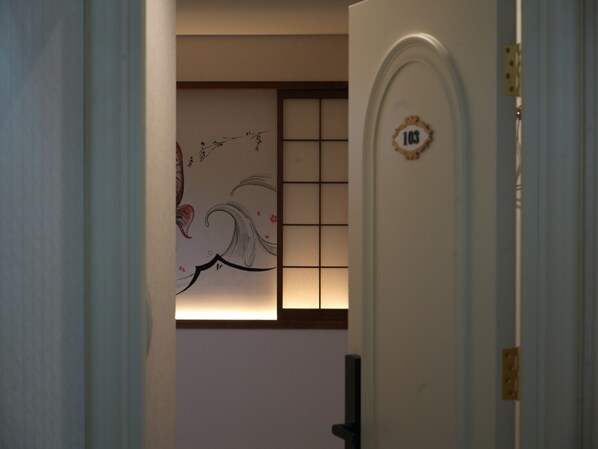 A hallway with a door marked 103, a traditional Japanese-style sliding door, and a wall with a floral painting.