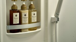 Une étagère de salle de bain avec trois bouteilles de produits de douche : du shampooing, un après-shampooing et du savon pour le corps.