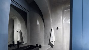 Ein modernes Badezimmer mit einem schwarzen Waschbecken, einem großen Spiegel und einem blauen Schrank.