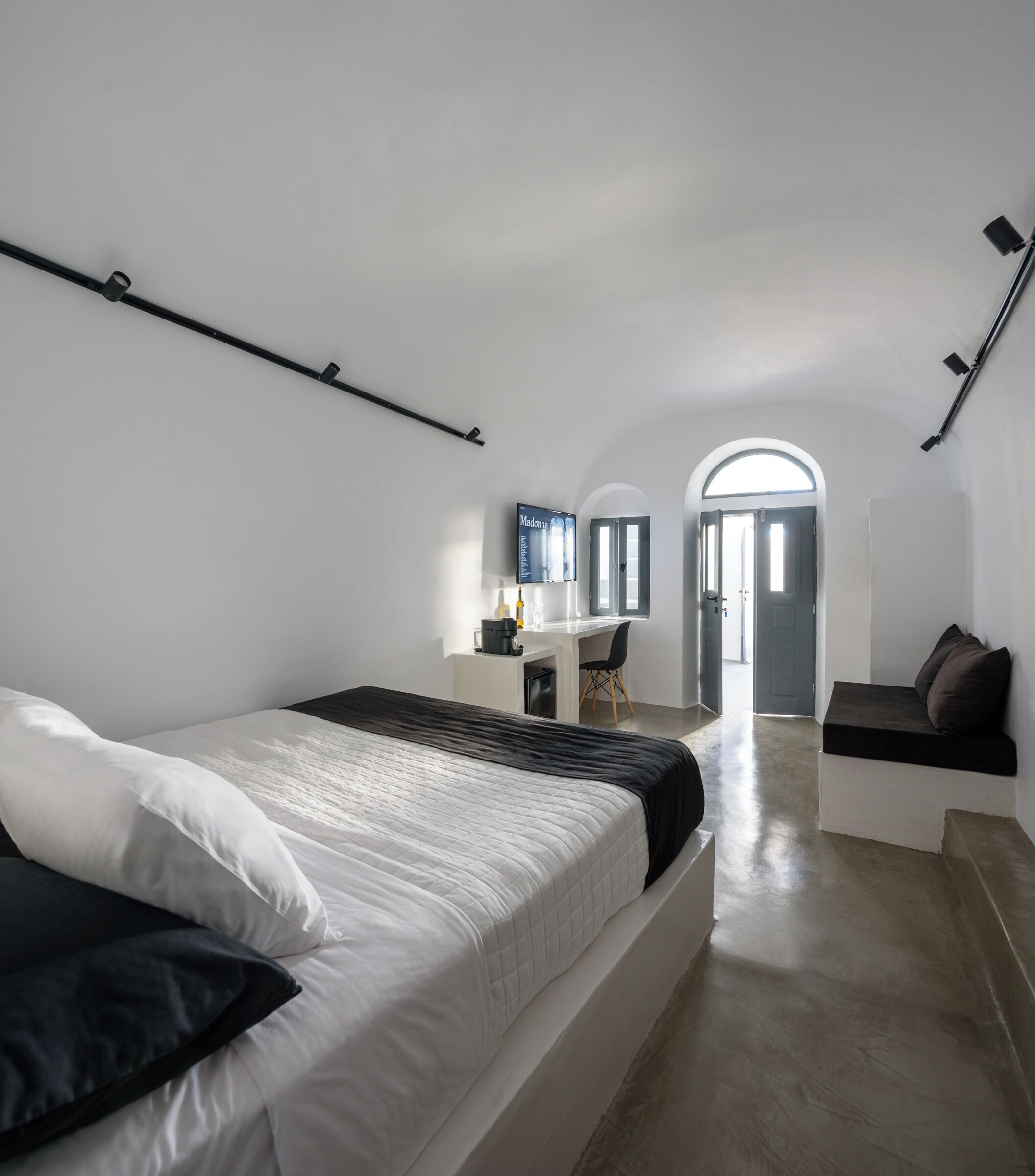 A modern bedroom with a bed, a desk, and a view of the outside.