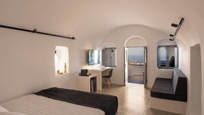 A modern bedroom with a bed, a desk, and a view of the city. - Domus Pyrgos (Santorini)