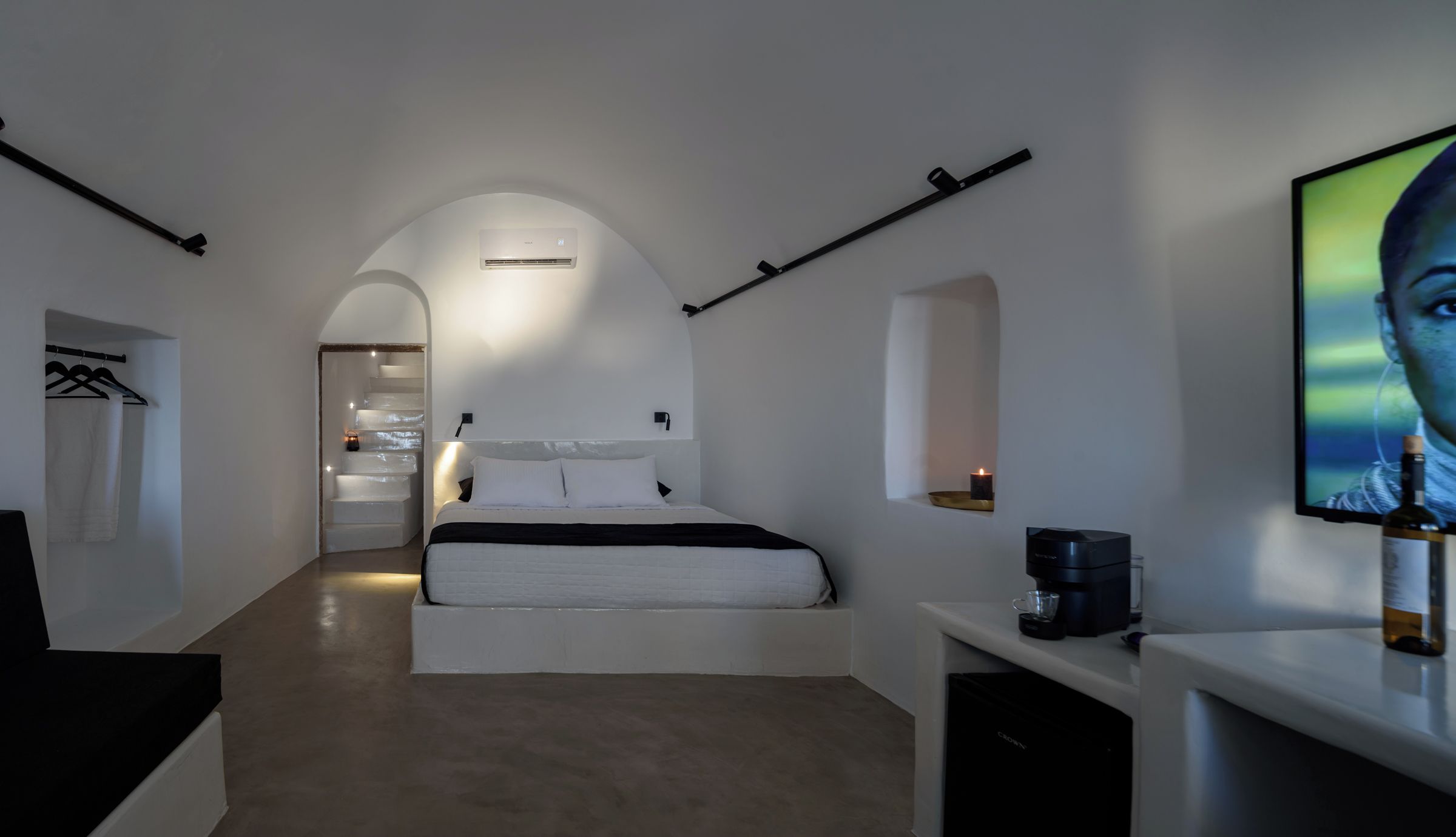 A modern hotel room with a large bed, a flat-screen TV, a coffee machine, and a small table.