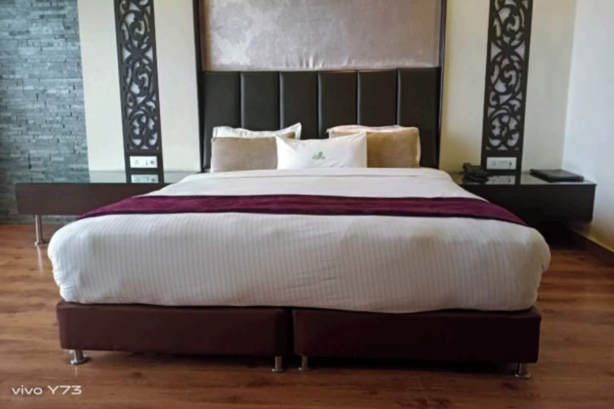 Una habitación de hotel con una cama grande, un cabecero oscuro y una pared de ladrillo.