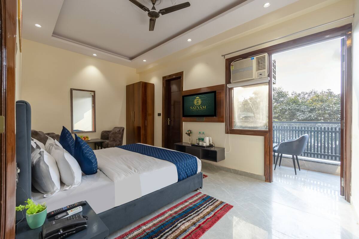 Una habitación de hotel moderna con cama, televisión, balcón y ventilador de techo.