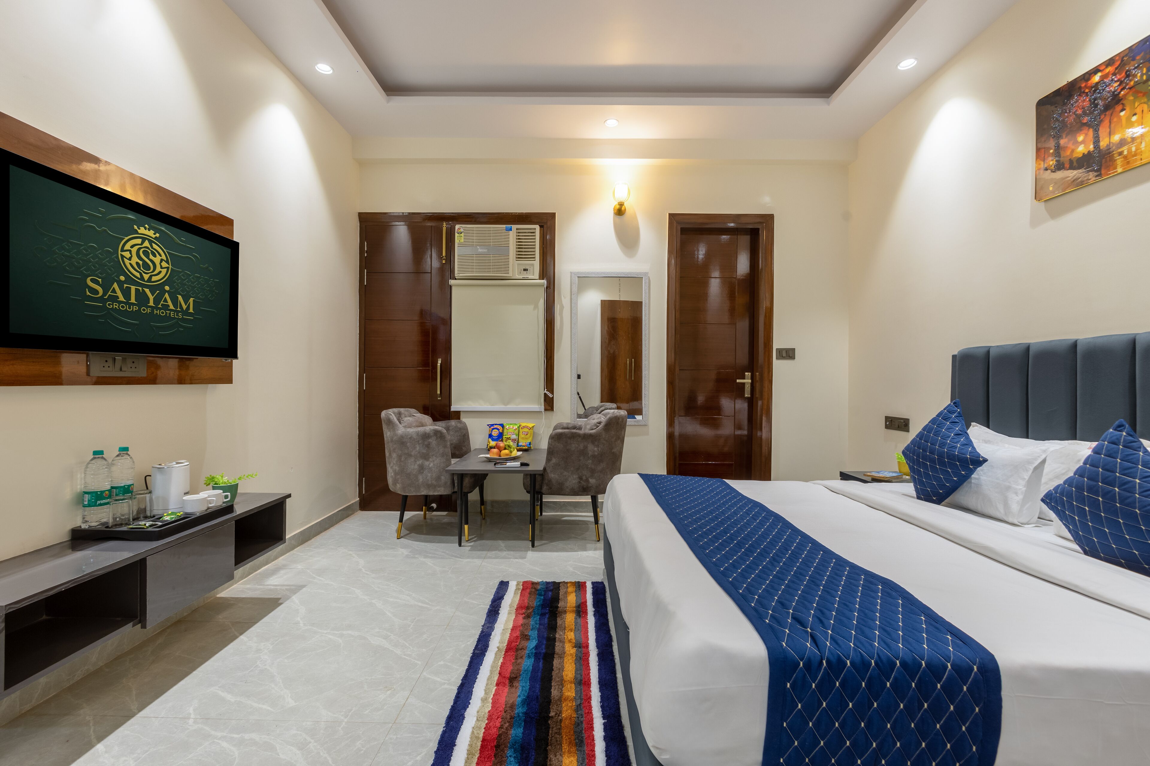 Una habitación de hotel con cama, escritorio, silla, televisor y espejo.