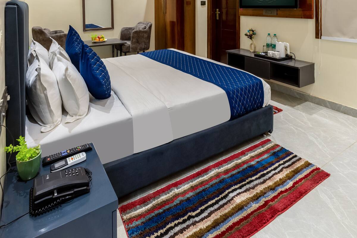 Una habitación de hotel con cama, escritorio, televisor y ventilador de techo.