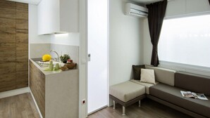 Een moderne woonruimte met een kitchenette, een bank en een raam met gordijnen.