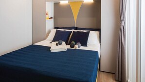 Een moderne slaapkamer met een bed, kussens en een nachtkastje.
